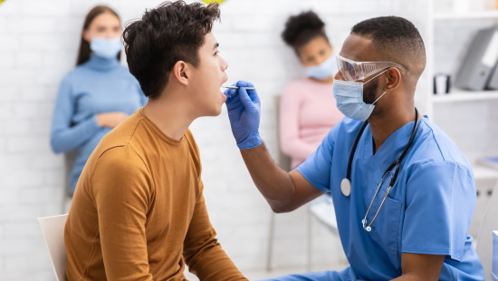 Doctor looking in mouth of teenager
