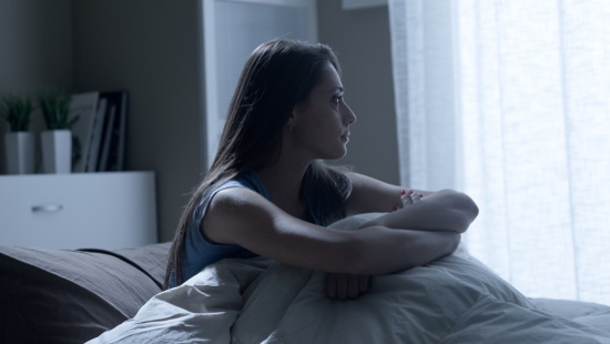 Woman sitting up in bed at night