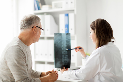 Spine surgeon examining spine x-ray with patient