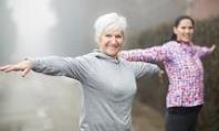 Two women stretching their arms out while outside exercising