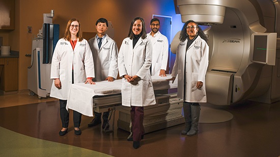 Physicians from the Radiation Oncology department in front of a linear accelerator.