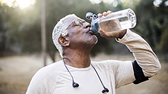 Older gentleman drinking water after exercising outdoors