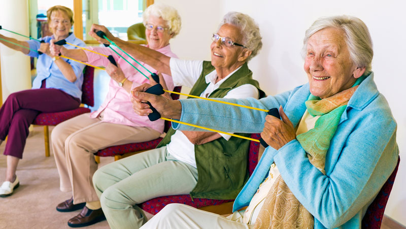 Older women sitting and using exercise bands with their arms