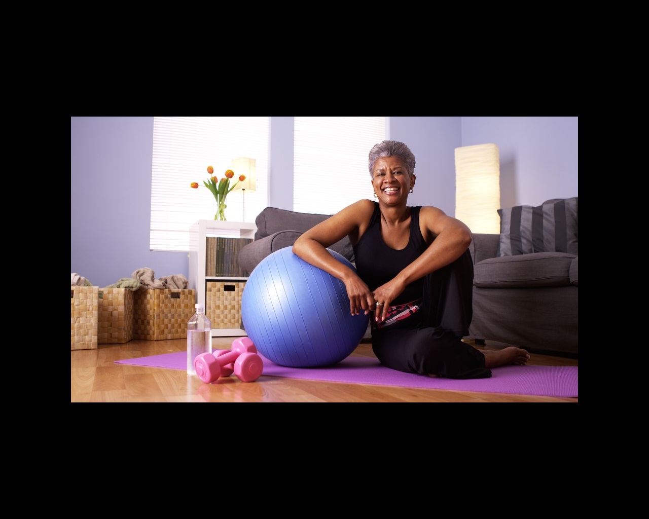 Woman exercising sitting next to an exercise ball
