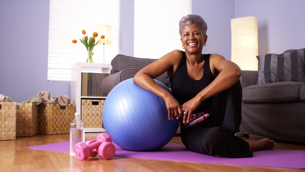 Woman exercising sitting next to an exercise ball
