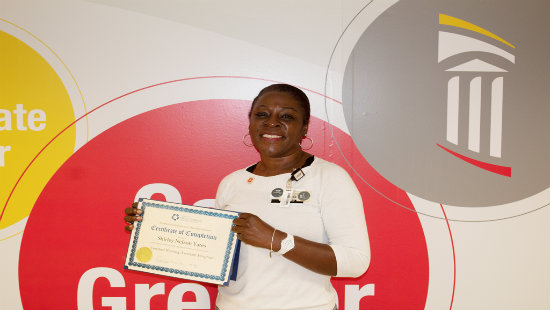 Employee smiling and holding certificate of achievement.