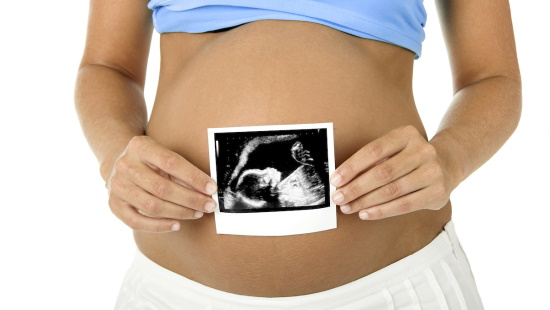 Pregnant woman holding ultrasound picture in front of her belly