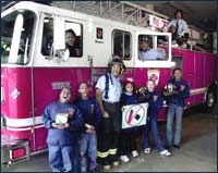 Photo of kids standing with a fireman in front of fire truck