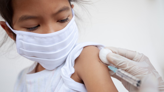 Girl in mask receiving a vaccine