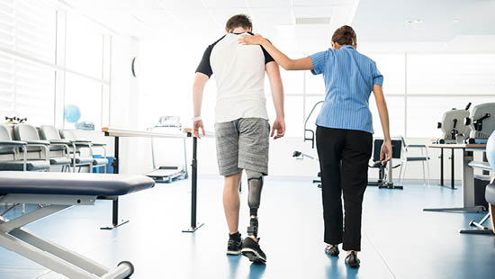 Healthcare worker walking next to man with leg amputation with their hand on their back for support