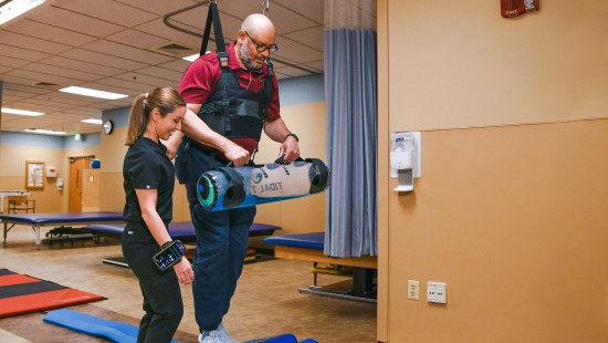 A patient taking steps during physical therapy with a neurologic physical therapist.