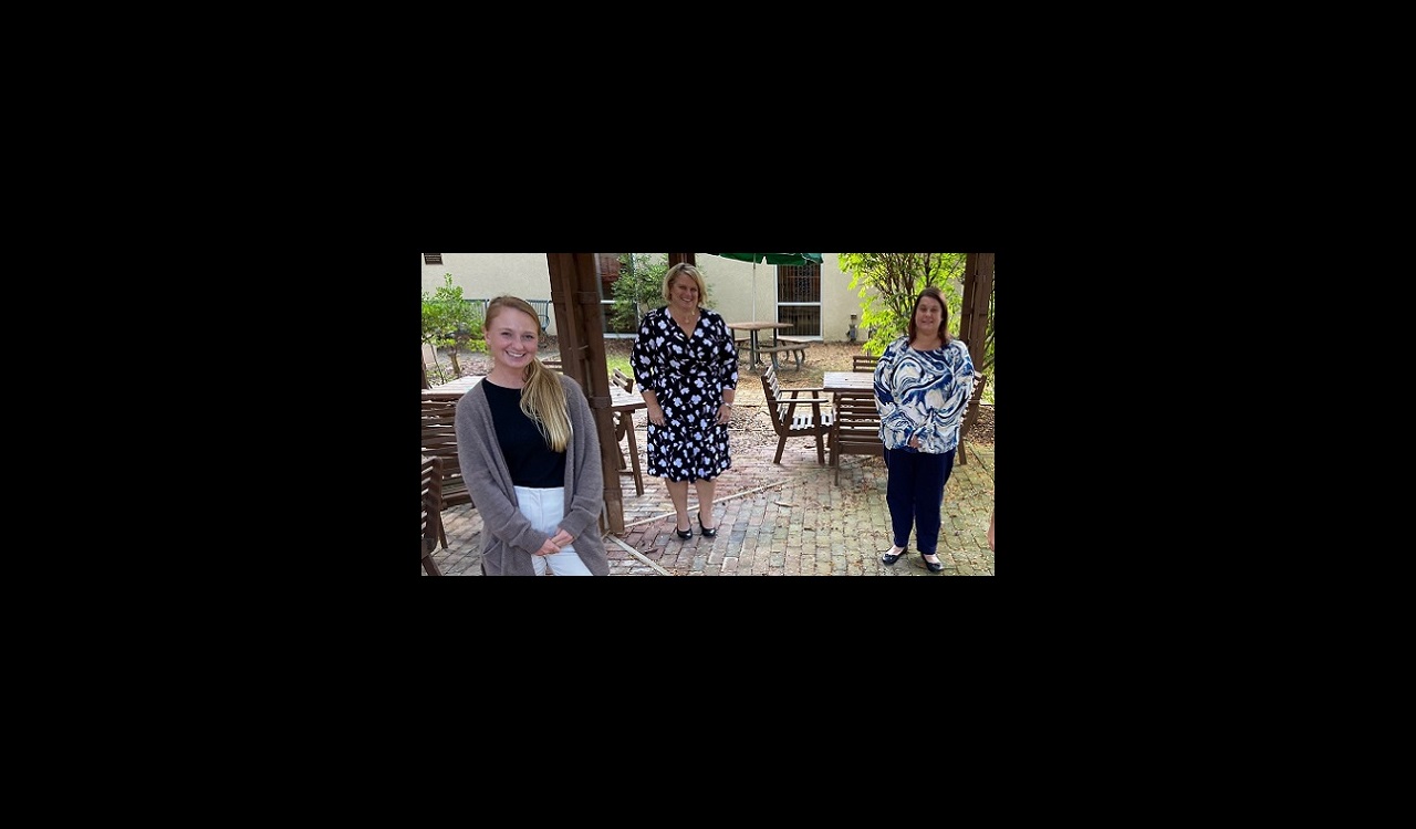 Three women stand outside under a gazebo, smiling. They are part of UM Shore Medical Center at Chestertown's Mobile Wellness Team.