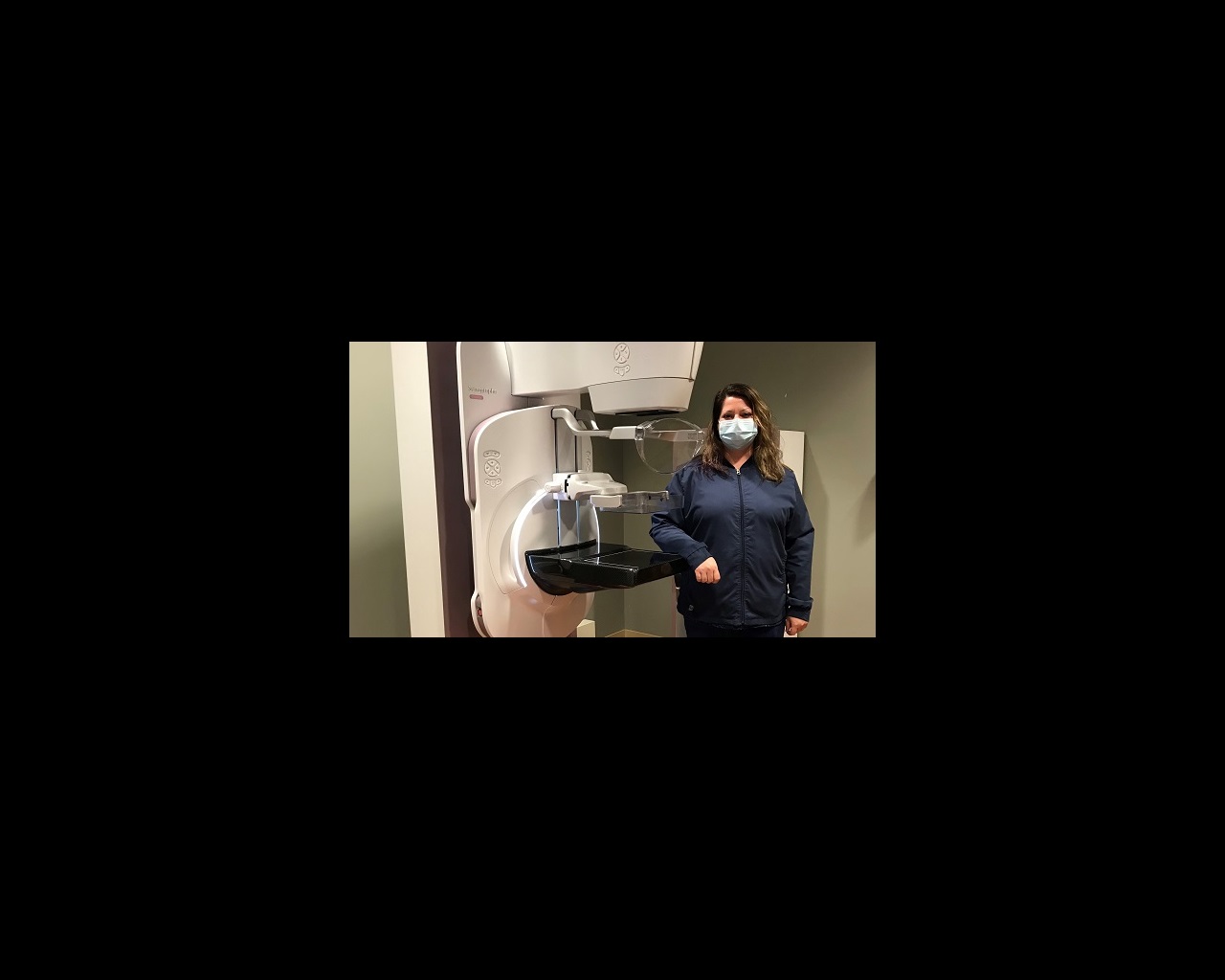 Holly Daly stands next to the Senographe Pristina Dueta mammography machine.