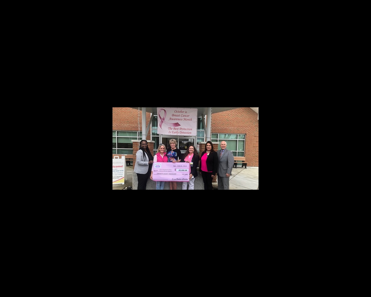 Six people stand in front of a sign that reads, "October is Breast Cancer Awareness Month. The Best Protection is Early Detection."