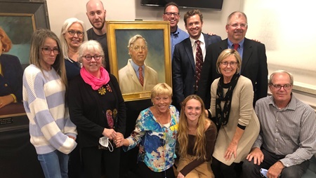 Eleven people stand around a portrait of Dr. Mickey Foxwell, a former doctor at Dorchester General Hospital.