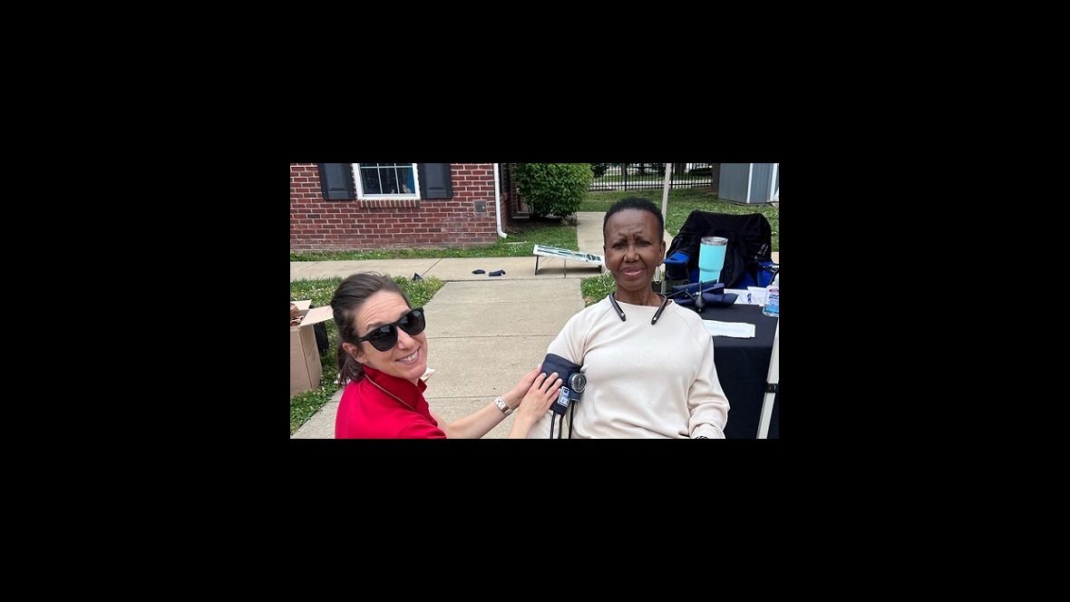 Emily Welsh takes Alma's blood pressure reading outdoors at an event.