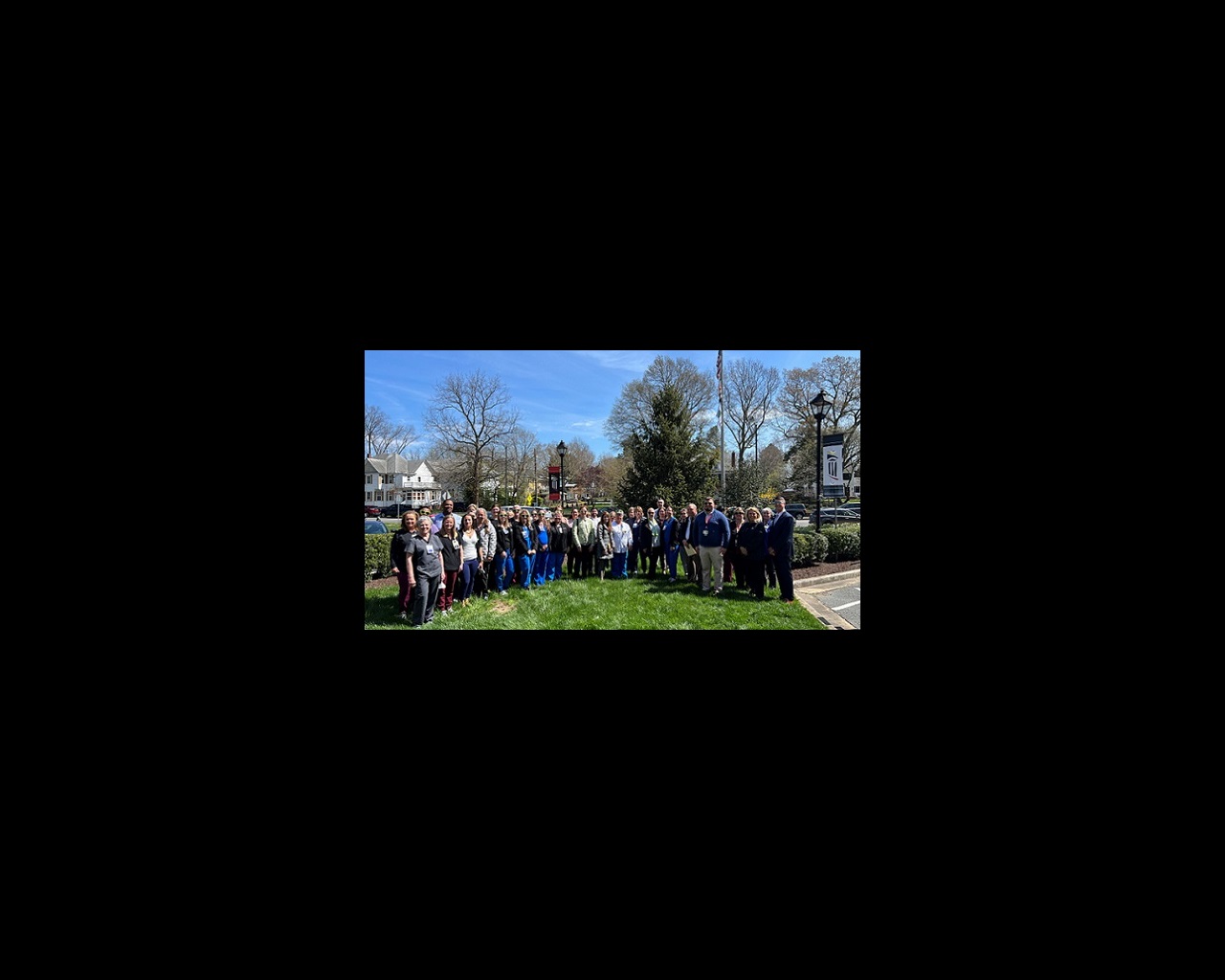 A large group of UM Shore Regional Health team members gathers on a bluebird day in the front circle of UM Shore Medical Center at Easton for the Donate Life flag-raising ceremony.