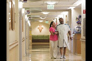 photo of a caregiver walking in the hallway with a patient