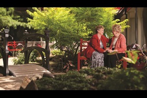 Photo of two women sitting on a bench comforting each other in the healing garden