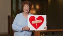 Woman holding a sign of a broken heart with a Band-Aid on it