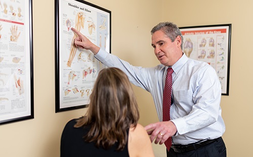 Physician speaking to patient pointing to diagram of the shoulder in reference to shoulder replacement
