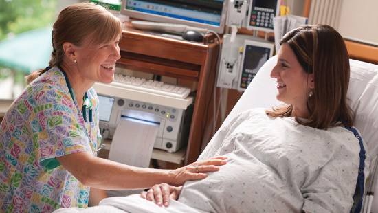 Nurse with pregnant woman in hospital bed
