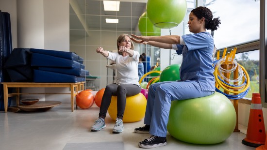 nurse helping patient use exercise ball