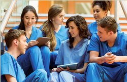 Group of students sitting on steps talking wearing scrubs