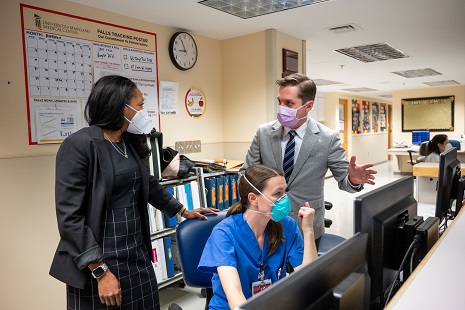 Cancer Center Faculty Members wearing masks interact while monitoring computers.