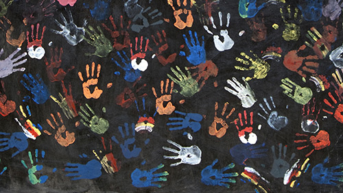 Hand prints in a variety of colors on a black background