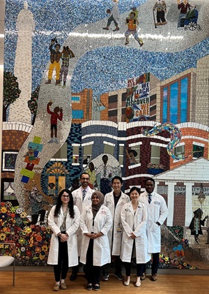 Group of people standing in front of a tiled mural