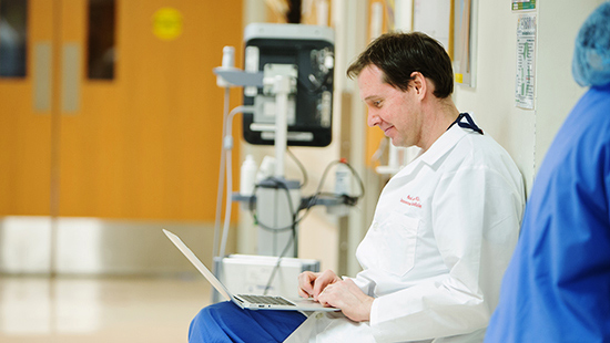 Heart Valve Regurgitation expert Mark Vesely, MD, sits with his laptop