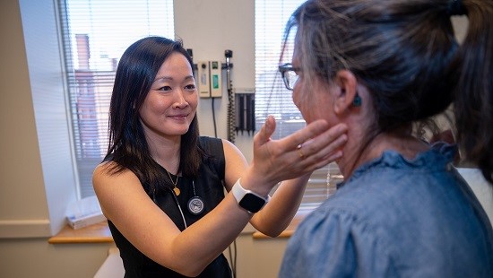 A health care specialist examining a patient, touching their neck.