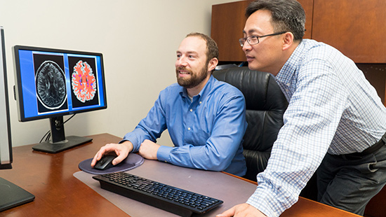 Dr. Harrison looking at brain scans with a research colleague