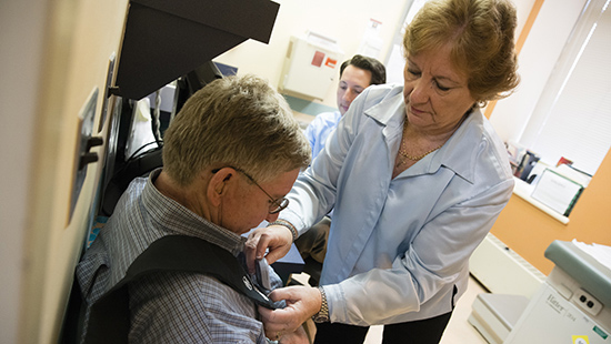 Parkinson's Disease Treatments | Sharon K. Powell, RN, MPH, helps a patient with equipment