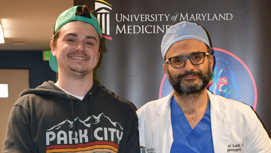 A photo of a smiling Kasey Trent who is standing next to Dr. Mohamed A. M. Labib, the neurosurgeon at the University of Maryland Medical Center who saved his life.