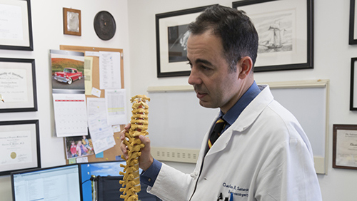 Dr. Charles Sansur holding a model of a spine