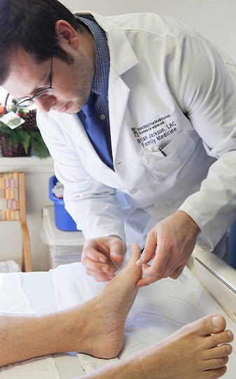 acupuncturist placing needles in foot
