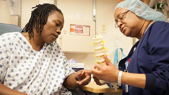 Patient and nurse talk while looking at a model of a spine