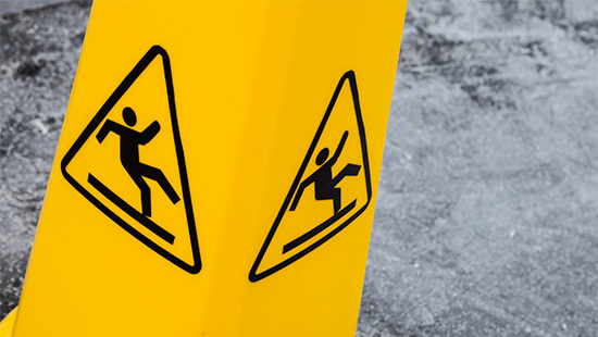 A photo of a yellow sign with a human silhouette falling backwards in the center of a black triangle.