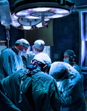 operating room with team of healthcare professionals working under the exam light