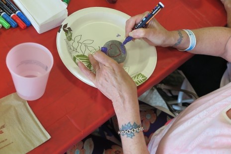 A view of a person's hands doing arts and crafts drawing on a rock