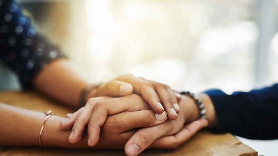 A picture of a person using their two hands to hold someone else's hand.