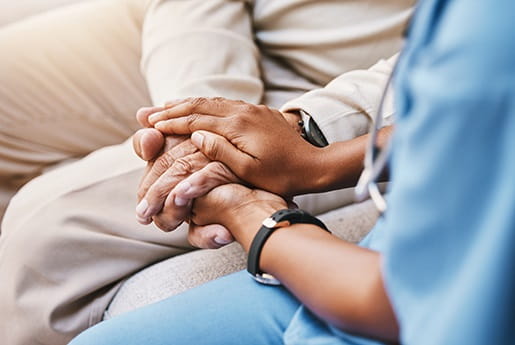 a nurse holds hands with a cancer patient