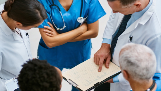 Team of doctors conferring while looking at medical chart