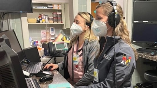 Two advanced practice providers do work at a computer station.